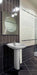 Bathroom with a white pedestal sink against a tiled wall.